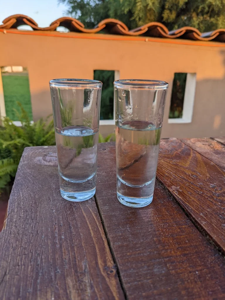 two shot glasses on outside table with clear liquid