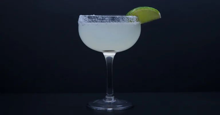 Margarita cocktail glass with salt rim and lime wedge garnish